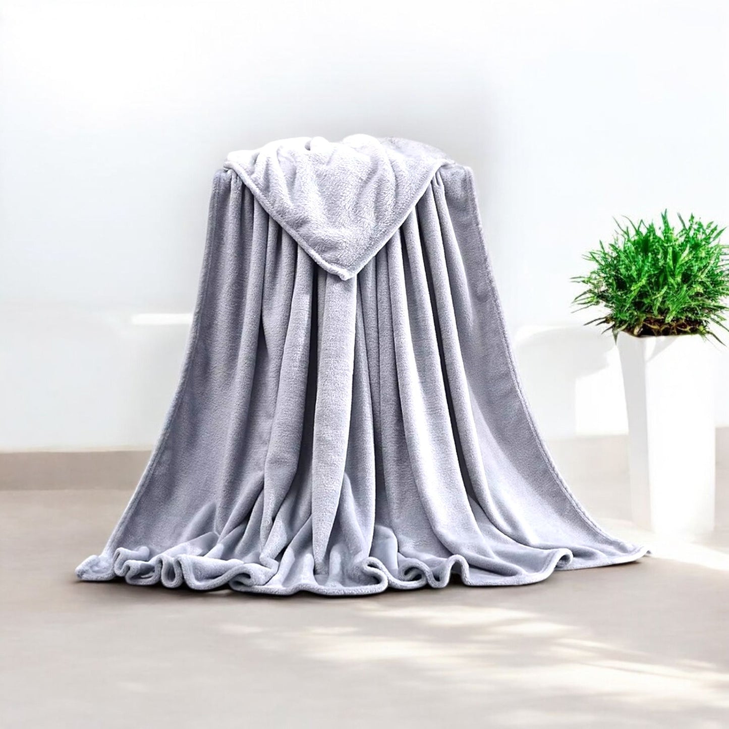 Gray blanket draped over a chair with a plant in the background