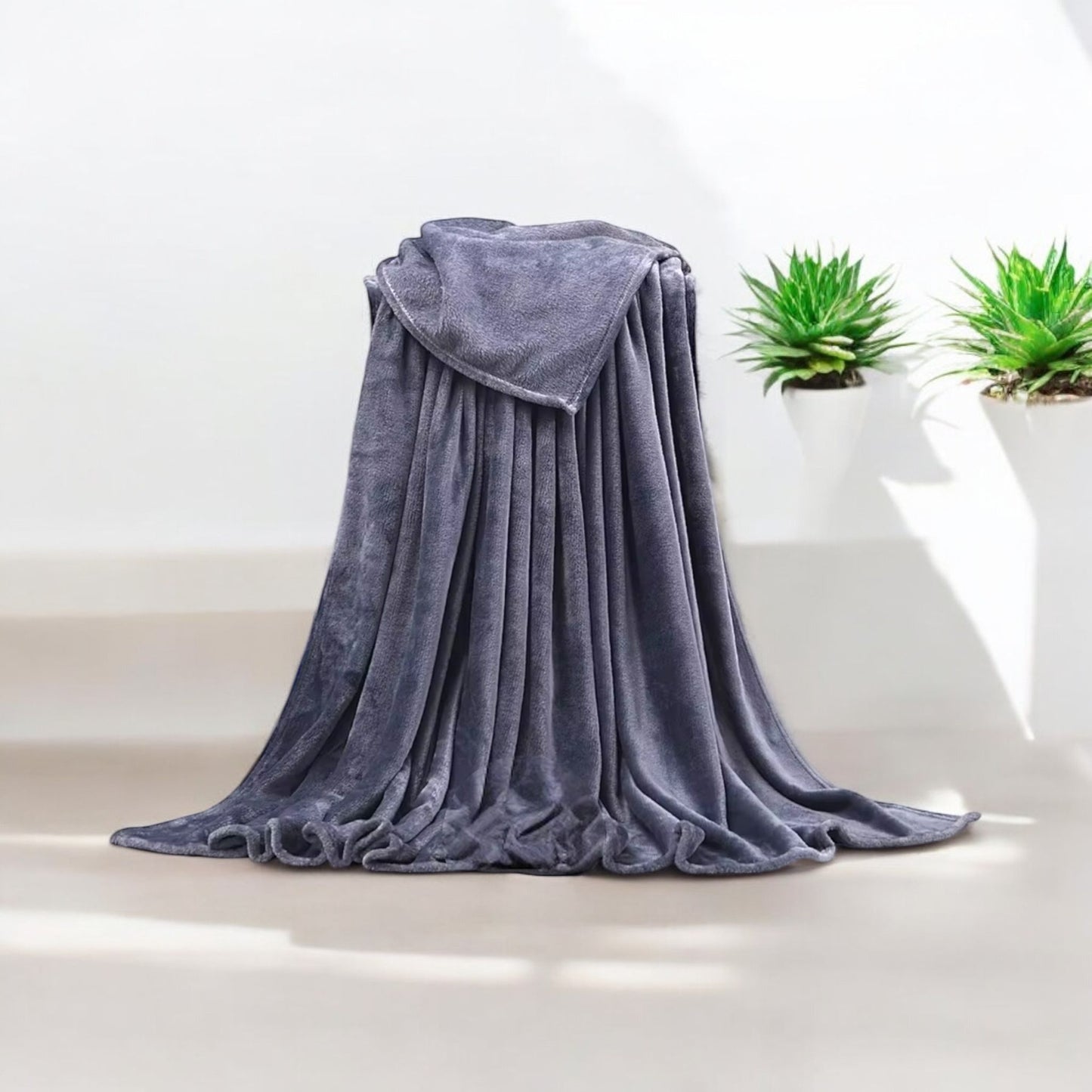 Gray blanket draped over a chair with two potted plants in the background